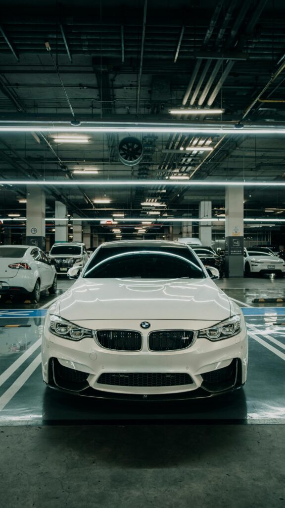 Stunning White BMW M3 Sport Sedan in Modern Parking Garage Mobile Wallpaper