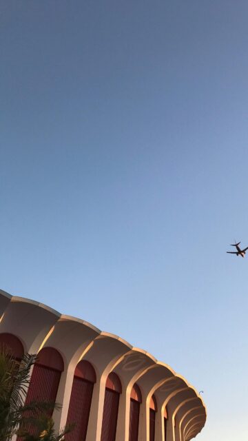 Airplane Soaring Over The Iconic Forum Arena Minimalist Sky Wallpaper