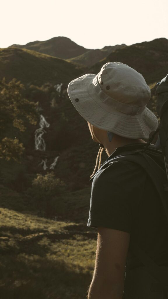 Adventurous Hiker Gazing at Mountain Waterfall Phone Wallpaper