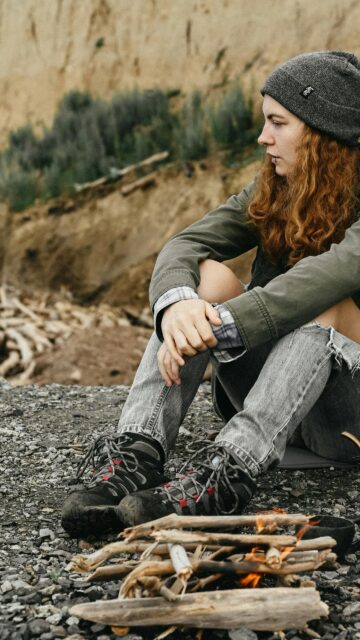 A Cozy Campfire Moment with a Red-Haired Hiker Mobile Wallpaper