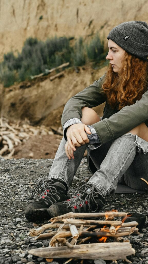 A Cozy Campfire Moment with a Red-Haired Hiker Mobile Wallpaper