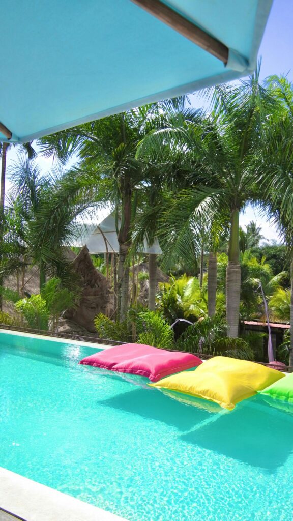 Floating Colorful Pool Pillows Under Tropical Palm Trees Wallpaper