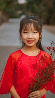 Cute Asian Girl in Traditional Red Ao Dai with Flowers Phone Wallpaper