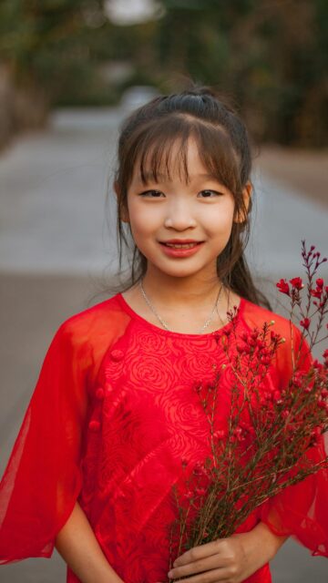 Cute Asian Girl in Traditional Red Ao Dai with Flowers Phone Wallpaper