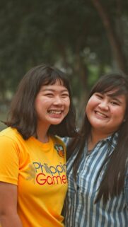 Two Smiling Asian Friends in Sunny Outdoor Setting Mobile Wallpaper