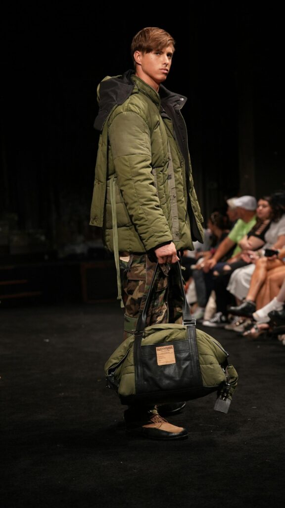 Military Fashion Runway Model with Green Puffer Bag Wallpaper