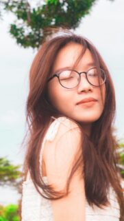 Dreamy Asian Girl with Glasses and Flowing Hair Mobile Wallpaper