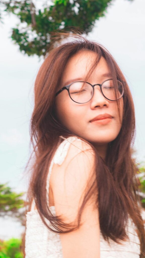 Dreamy Asian Girl with Glasses and Flowing Hair Mobile Wallpaper