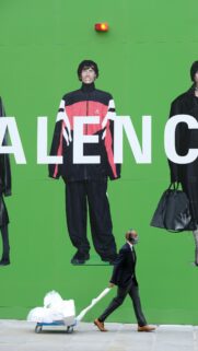 Man Walking Past Iconic Green Balenciaga Street Fashion Billboard Wallpaper
