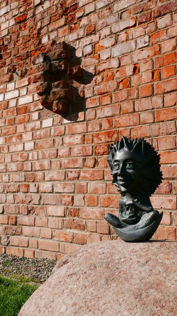 Mystical Bronze Goblin Statue on Stone Wall Background Wallpaper