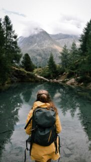 Woman Hiker Standing by Serene Mountain Lake Mobile Wallpaper