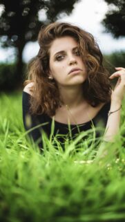 Stunning Portrait of a Young Woman in Lush Green Grass Phone Wallpaper