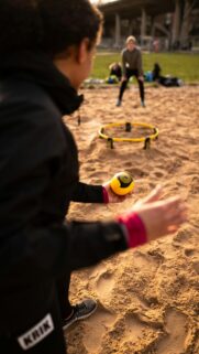 Spikeball Player Preparing for Serve on Sandy Beach Mobile Wallpaper