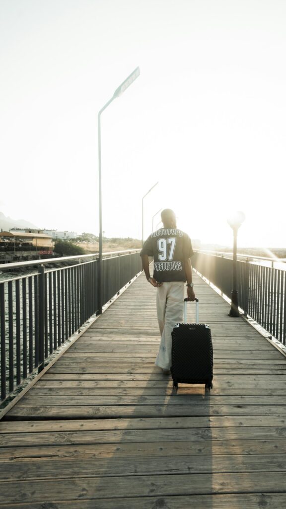 Man Walking on Sunny Wooden Pier with Suitcase Mobile Wallpaper