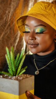 Stylish Woman with Vibrant Eyeshadow and Potted Succulent Wallpaper