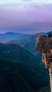 Lone Hiker on Mountain Cliff Edge Sunset Mobile Wallpaper