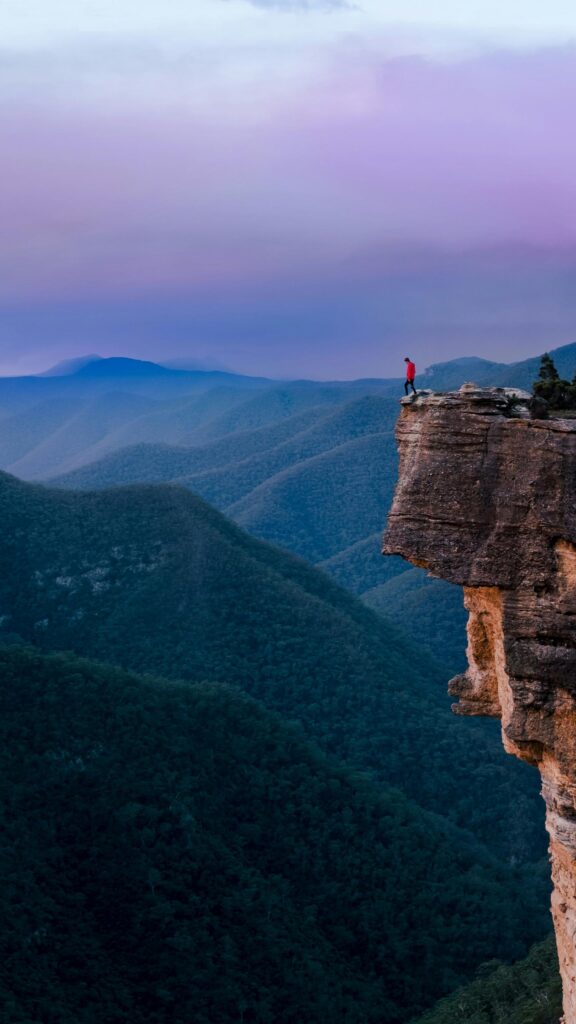 Lone Hiker on Mountain Cliff Edge Sunset Mobile Wallpaper