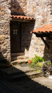 Rustic Stone House Entrance with Classic Wagon Wheel Mobile Wallpaper