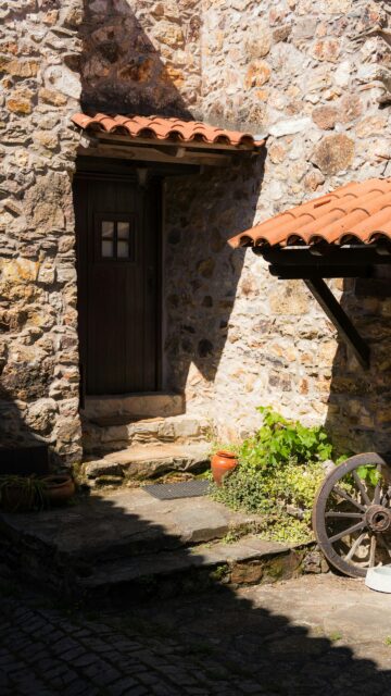 Rustic Stone House Entrance with Classic Wagon Wheel Mobile Wallpaper