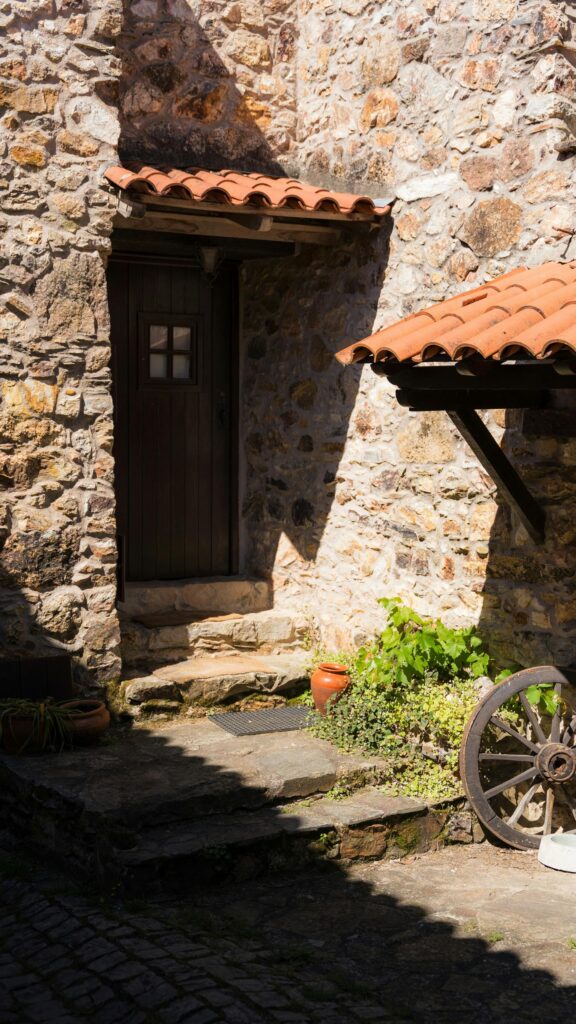 Rustic Stone House Entrance with Classic Wagon Wheel Mobile Wallpaper