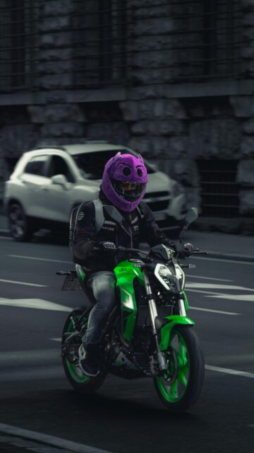 Neon Green Motorcycle Rider with Purple Monster Helmet Wallpaper