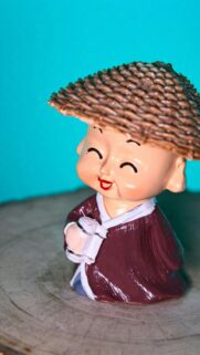 Cute Little Monk Statue with Traditional Straw Hat 4K Mobile Wallpaper