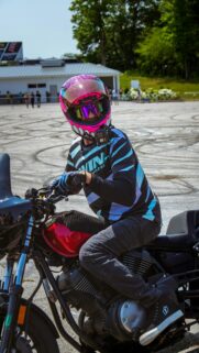 Stunt Rider in Vibrant Pink Monster Helmet on Motorcycle Wallpaper