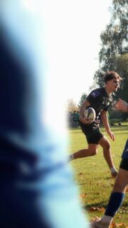 Young Rugby Player Running with Ball on Sunny Field Mobile Wallpaper