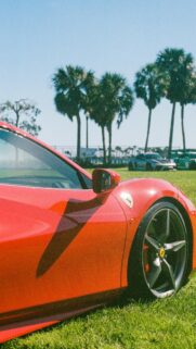 Stunning Red Ferrari Sports Car on Grass Field Mobile Wallpaper