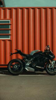 Black Ducati Panigale V4 Superbike Against Industrial Red Container Wallpaper