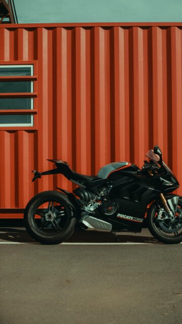 Black Ducati Panigale V4 Superbike Against Industrial Red Container Wallpaper