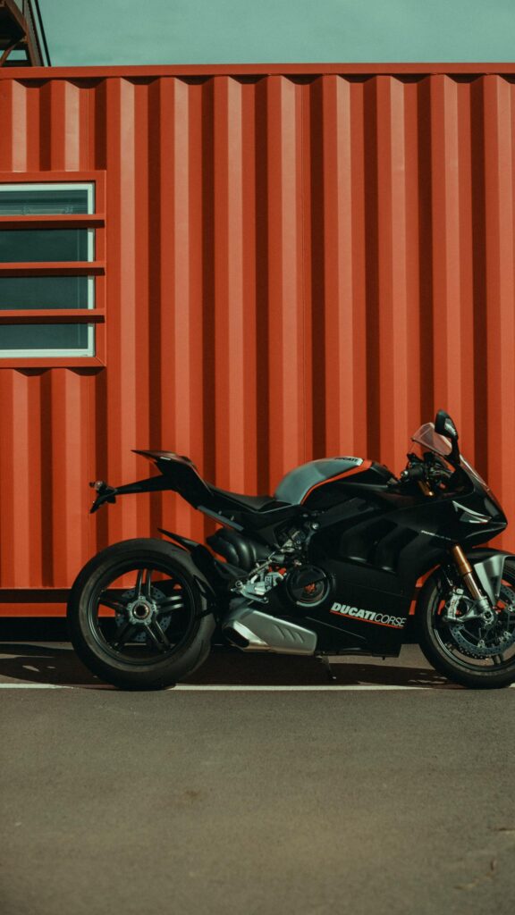 Black Ducati Panigale V4 Superbike Against Industrial Red Container Wallpaper