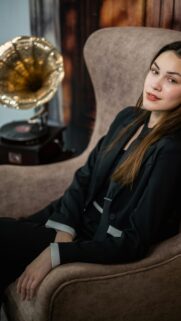Elegant Woman in Black Suit Sitting in Vintage Chair Wallpaper