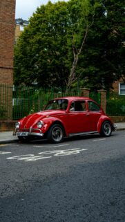 Classic Red Volkswagen Beetle parked on a City Street Wallpaper