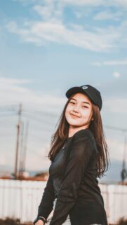 Smiling Girl Wearing a Blue Cap in Soft Outdoor Light Mobile Wallpaper