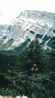 Adventurous Hiker Before Majestic Snowy Mountain Peak Wallpaper