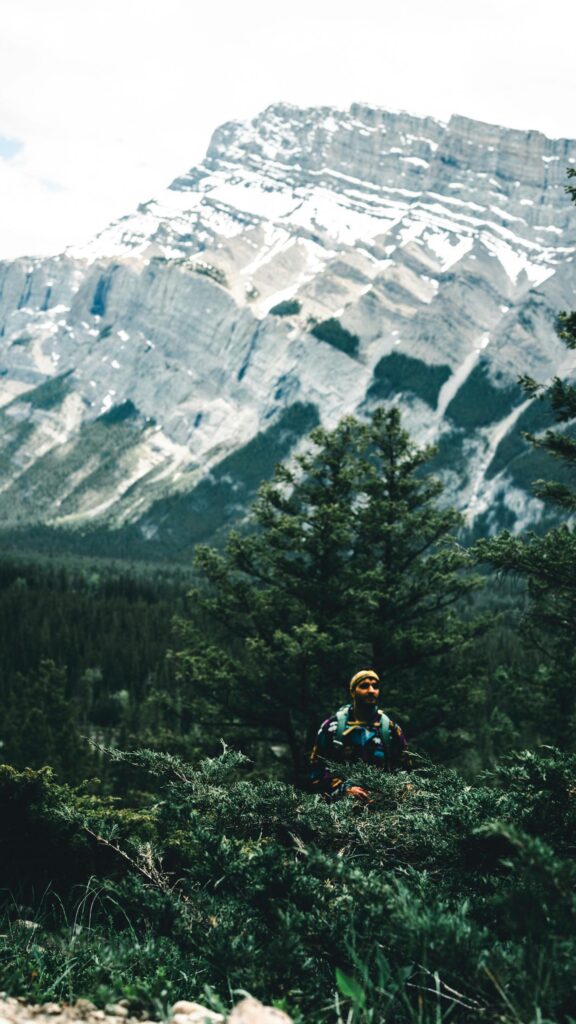 Adventurous Hiker Before Majestic Snowy Mountain Peak Wallpaper
