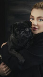 Stunning Portrait of a Woman Holding a Cute Black Pug Dog Wallpaper