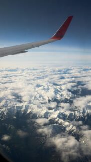 Stunning Snowy Mountain Range Above Clouds View from Airplane Window Wallpaper
