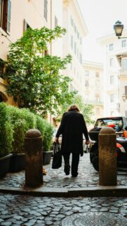 Woman Walking Through Cobblestone Roman Street Mobile Wallpaper