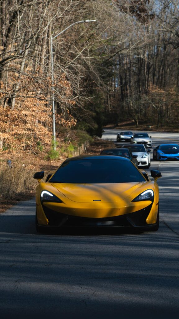 Stunning Yellow McLaren Supercar Driving in a Fleet of Luxury Sports Cars Wallpaper