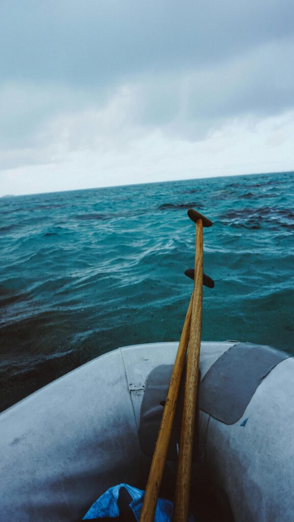 Serene Ocean Voyage with Wooden Paddles in Inflatable Boat Wallpaper
