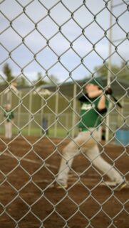 Baseball Player Batting Through Chain Link Fence Phone Wallpaper