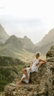 Ethereal Woman in White Dress on Mountain Cliff Mobile Wallpaper
