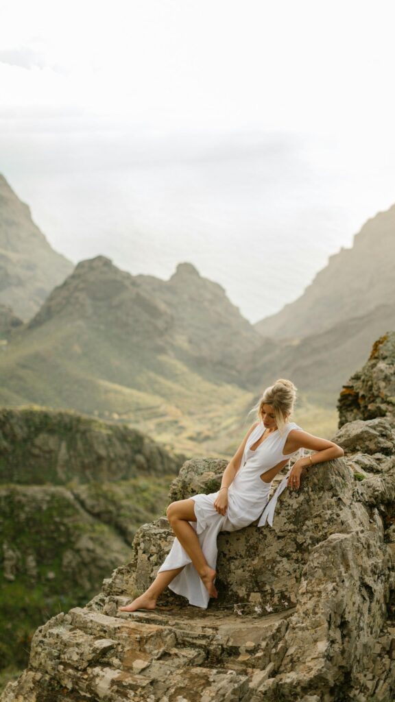 Ethereal Woman in White Dress on Mountain Cliff Mobile Wallpaper