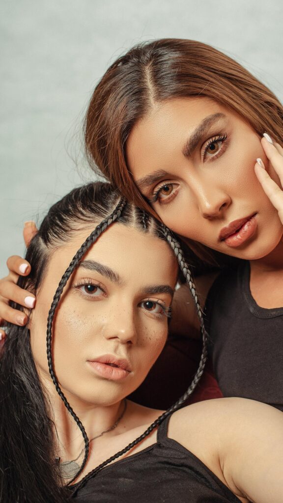 Elegant Duo Portrait with Braided Hairstyles Mobile Wallpaper