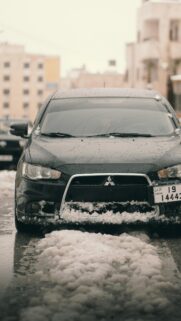 Black Mitsubishi Lancer in Snowy Winter Street Phone Wallpaper