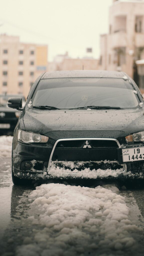 Black Mitsubishi Lancer in Snowy Winter Street Phone Wallpaper