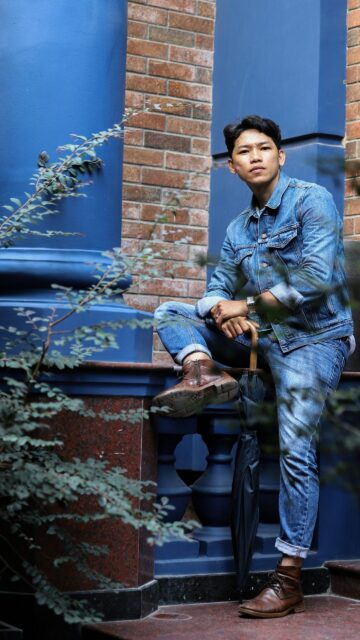 Stylish Man in Denim Sitting on Blue Balustrade HD Mobile Wallpaper