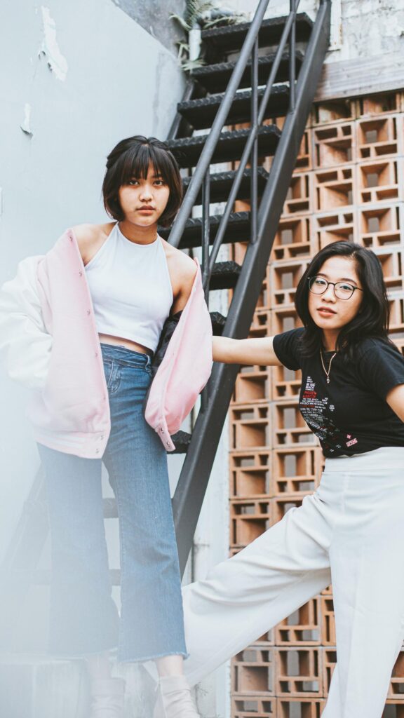 Stylish Asian Friends Posing on Industrial Metal Stairs Wallpaper